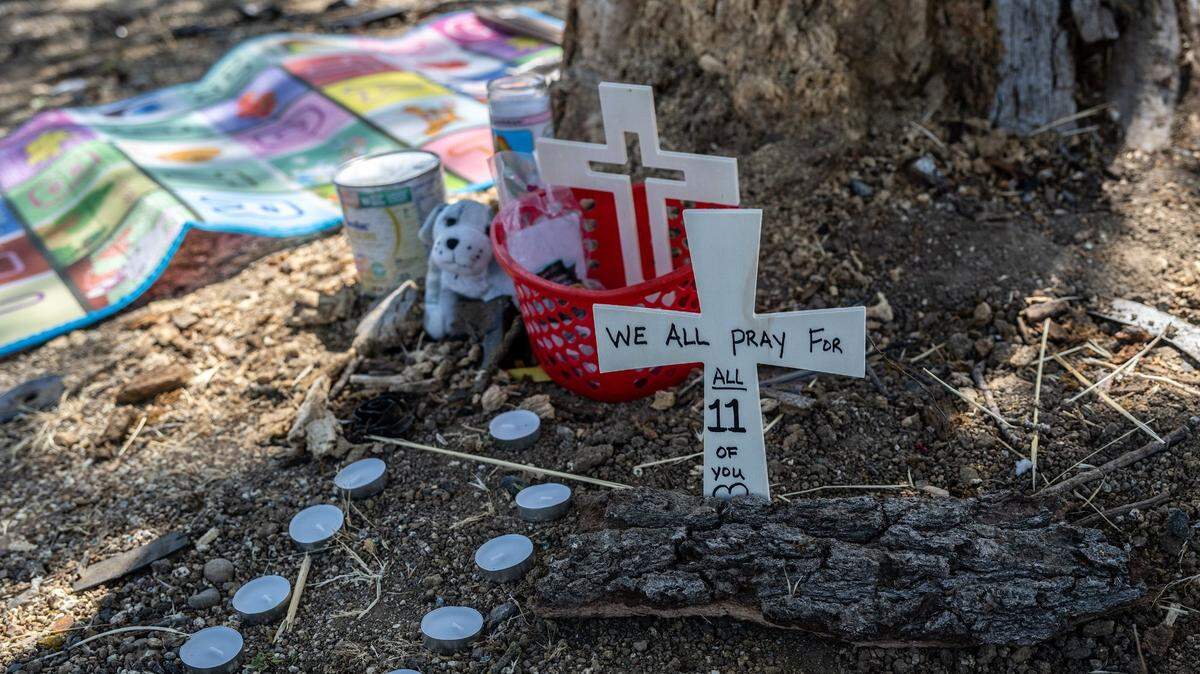 Eleven candles, flowers, and crosses lie on Thursday, June 1, 2023, near the tree where three people died and eight were injured along San Juan Road in Sacramento the night before.