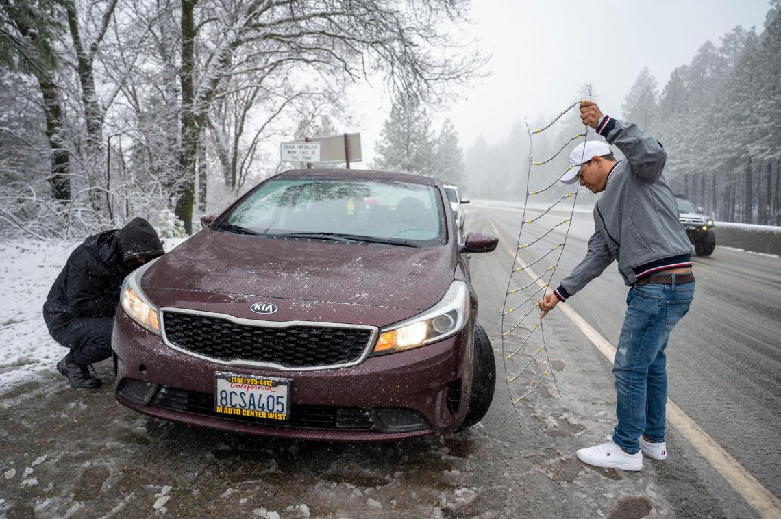 William Membreno of San Jose puts on chains along Highway 50 near Camino on Saturday, March 2, 2024.