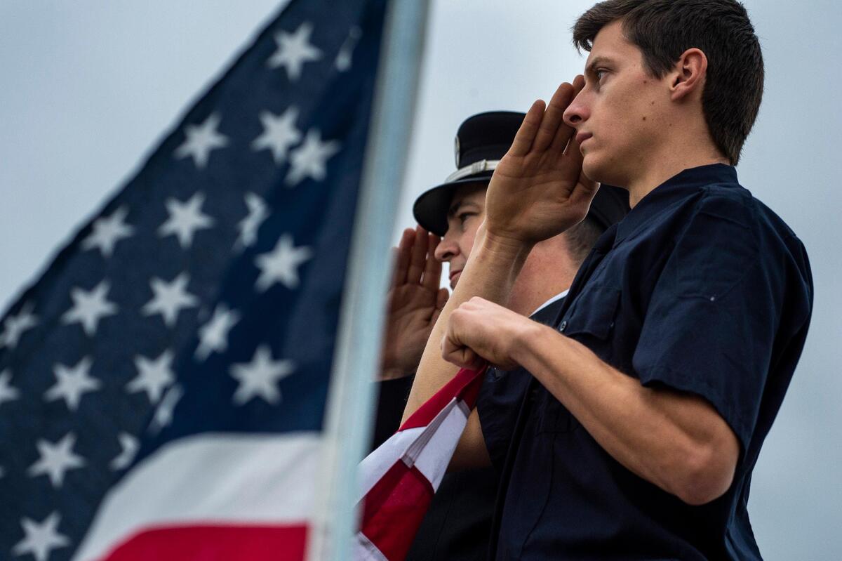Joseph Beregovoy, right, and Andrew Lewis salute during the procession for fallen Davis police officer Natalie Corona on Highway 113 after the memorial services Friday.