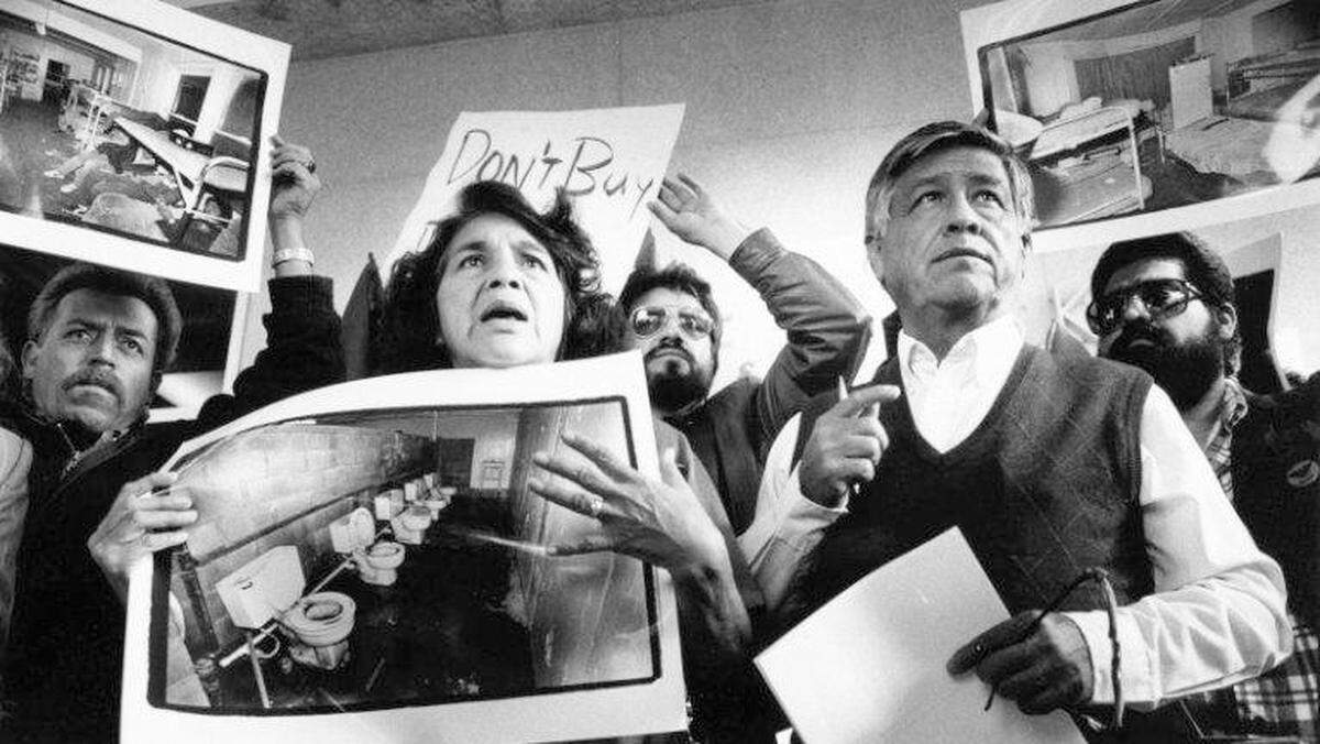 United Farm Workers leaders Dolores Huerta and Cesar Chavez display photos of the conditions that farmworkers endure in San Joaquin Valley farm labor camps at a news conference outside U.S. District Court in Fresno in 1989. 