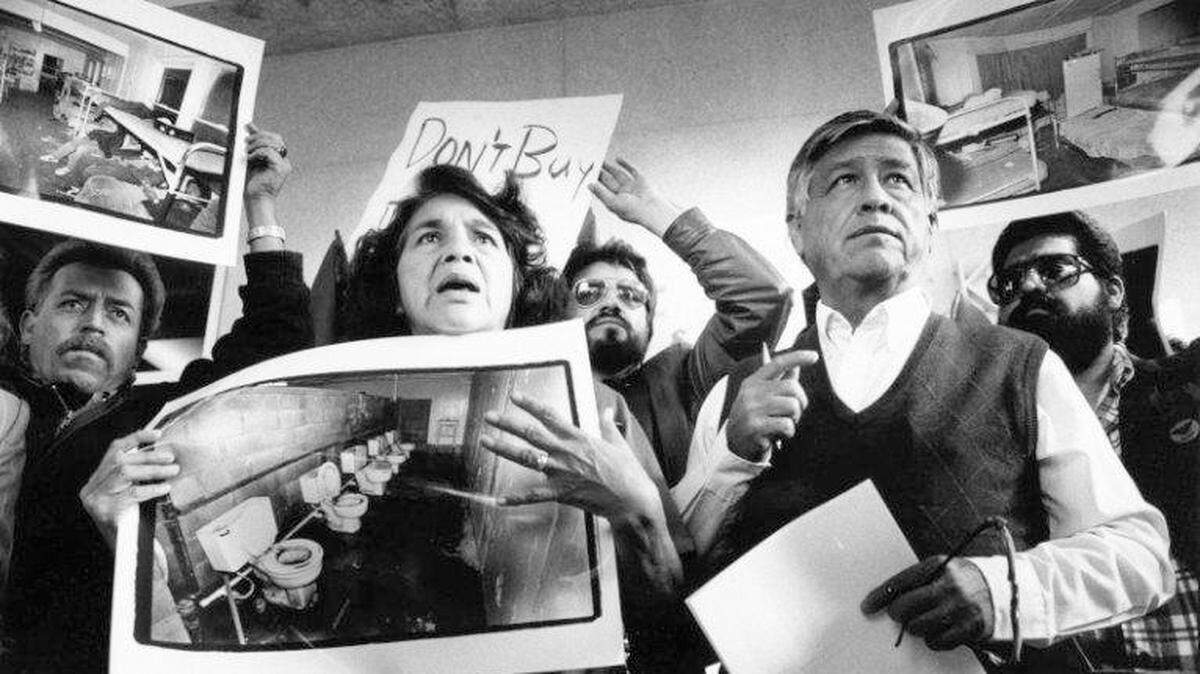 United Farm Workers leaders Dolores Huerta and Cesar Chavez display photos of the conditions that farmworkers endure in San Joaquin Valley farm labor camps at a news conference outside U.S. District Court in Fresno on Tuesday, Nov. 21, 1989.