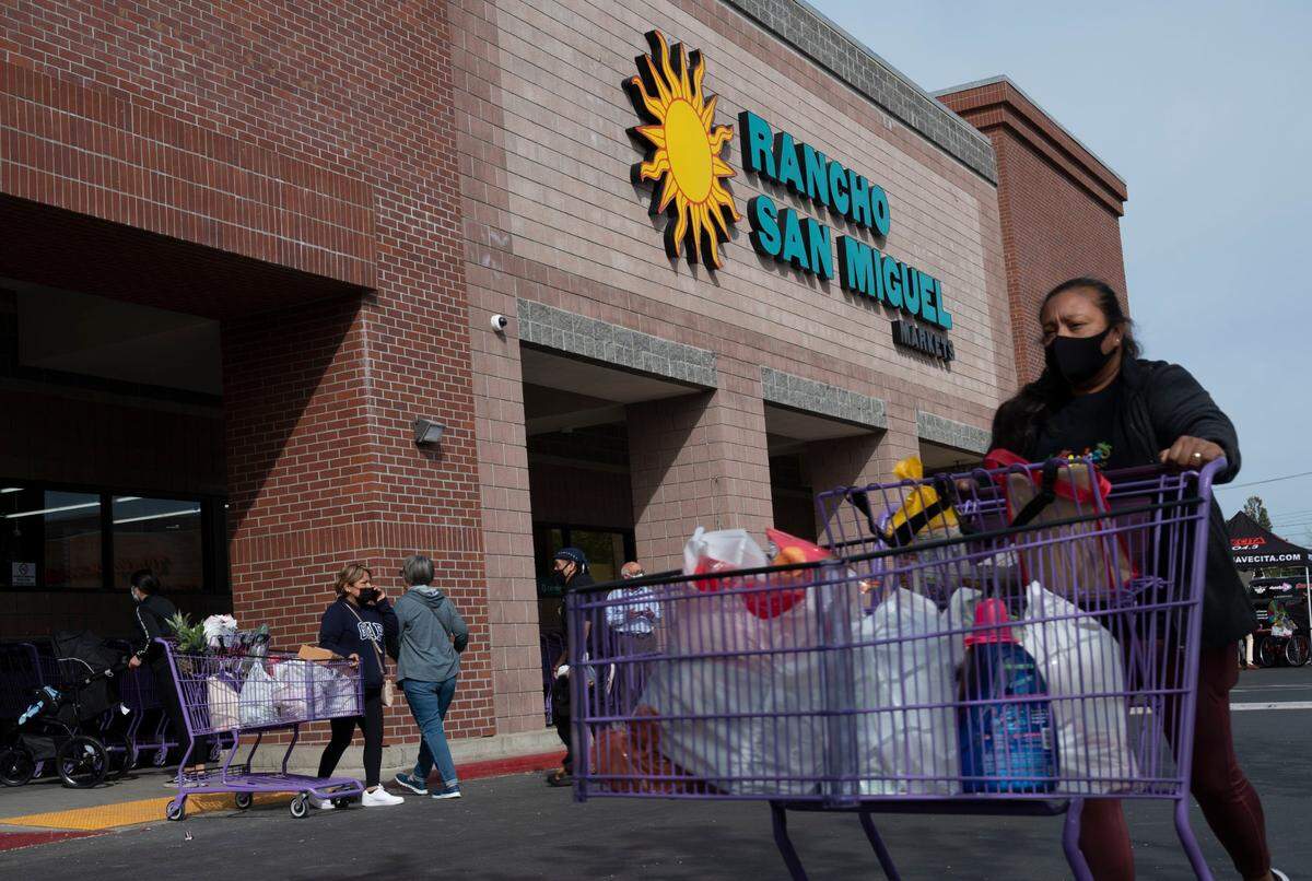 Customers leave with their purchases during the grand opening of Rancho San Miguel Market.
