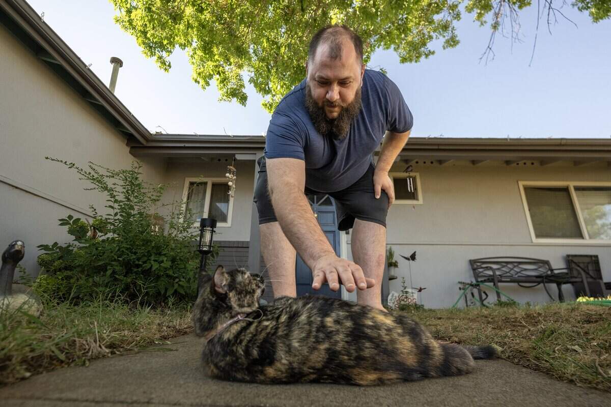 Chris Commander embraces his cat Xena on Wednesday in Rancho Cordova.