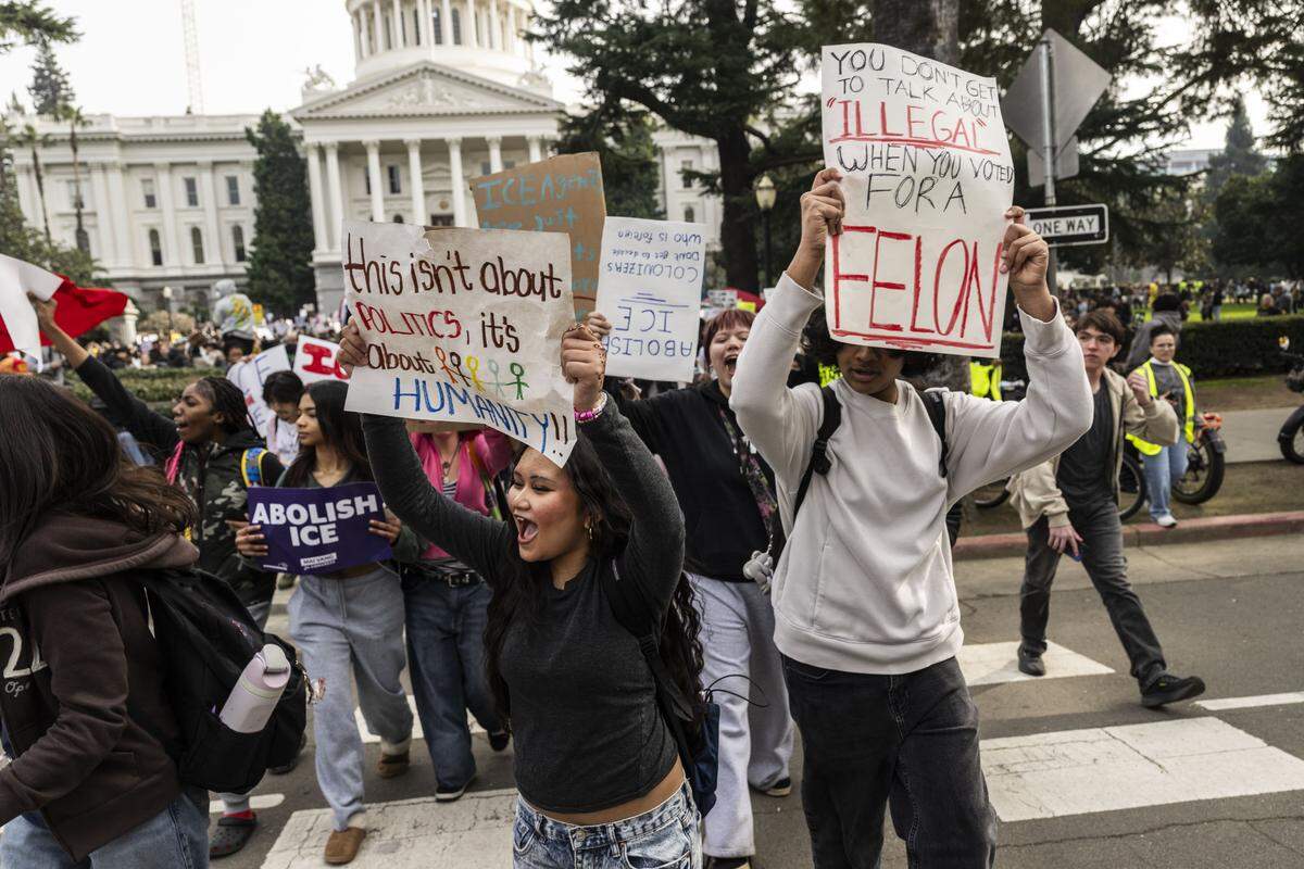 Students carry signs as they march to the John E. Moss Federal Building during a protest against ICE at the state Capitol on Friday.
