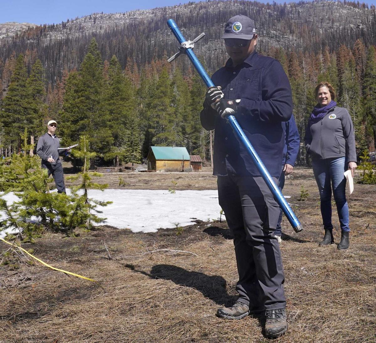 Holding the snowpack measuring tube, Sean de Guzman, manager of snow surveys and water supply for the Department of Water Resources, looks down at the ground where there would normally be snow to measure at Friday’s fourth and final snow survey of the year at Phillips Station.