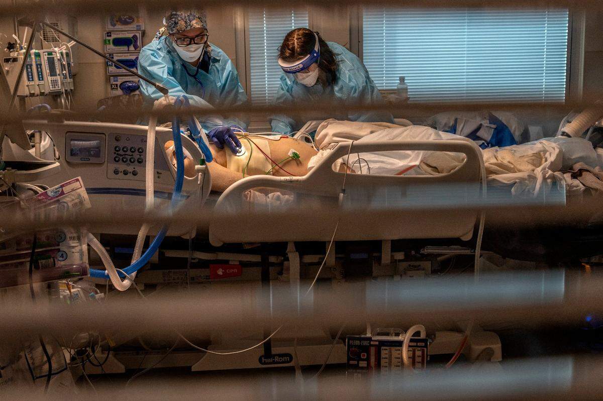Registered nurse Carina Klescewski, left, and phlebotomist lab assistant Jennifer Cukati care for a very sick COVID-19 patient inside Sutter Roseville Medical Center ICU on Tuesday, Dec. 22, 2020. The patient came in the night before with “code blue” and COVID-19 positive. His heart stopped and he had to be intubated and is on a ventilator. “We are seeing extremely sick people,” said Doctor Imran Mohommed, ICU Medical Director. He said they have the capacity right now to handle patients but will be challenged if more arrive in ICU.