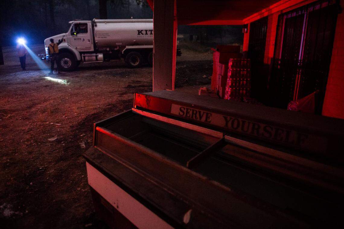 Cal Fire contractors tend water in front of an empty business off Lumpkin Road as the Bear Fire burns nearby Wednesday, Sept. 9, 2020, in Butte County.
