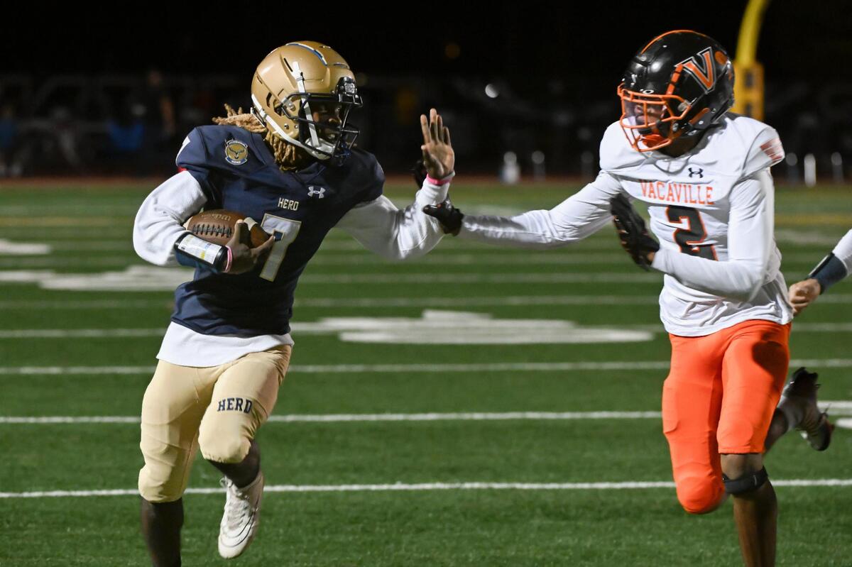 The Elk Grove Thundering Herd’s Jeremiah Williams (7) runs the ball for a first down before being pushed out of bounds by the Vacaville Bulldogs’ Jemeir Buckner (2) in the first half of a first-round CIF Sac-Joaquin Division II section football playoff game on Friday.