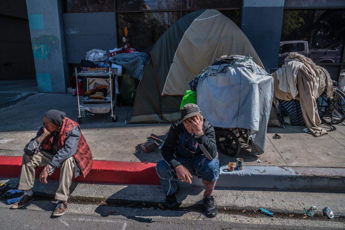 Larry Robert Walsh, 51, center, sits with a severely injured leg with all his belongings behind him on 10th Street in downtown Sacramento on March 16. “It’s really a difficult moment,” said Walsh, who had been camping on that block for the past week.