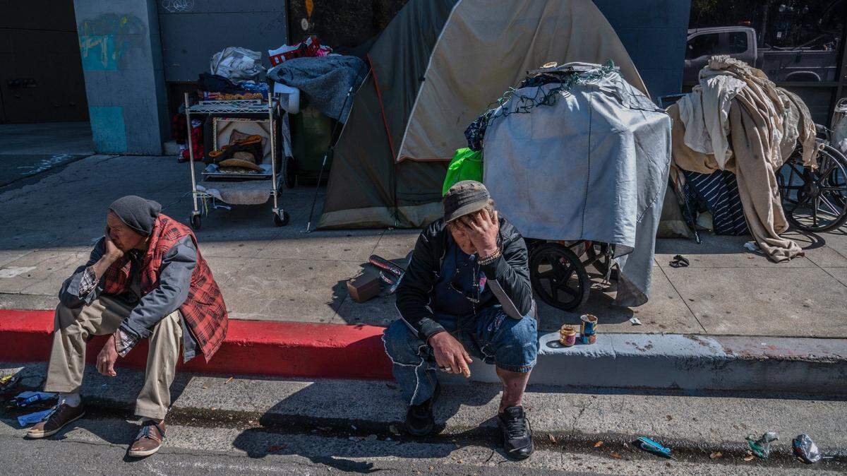 Larry Robert Walsh, 51, center, sits with a severely injured leg with all his belongings behind him on 10th Street in downtown Sacramento on Tuesday, March 16, 2021. “It’s really a difficult moment,” said Walsh, who had been camping on that block for a week.