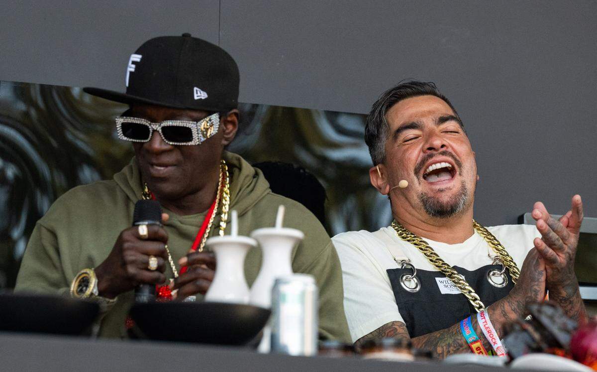 Celebrity chef Aarón Sánchez, right, laughs as rapper Flavor Flav demonstrates a secretive fried chicken recipe on the Williams Sonoma Culinary Stage at the BottleRock music festival in Napa on Friday, May 23, 2025. 