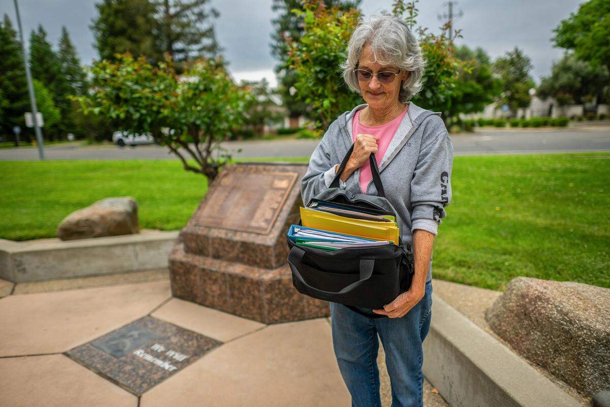 Lisa Covington Bubienko holds a bag containing binders of historical information, which she uses in her role as a coordinator of memorials for the 1976 bus crash, at the Yuba City memorial site on Monday. This year marks the 50th anniversary of the crash that killed 28 Yuba City High School choir students and a teacher. Bubienko was a sophomore at the high school and on campus when the crash occurred.