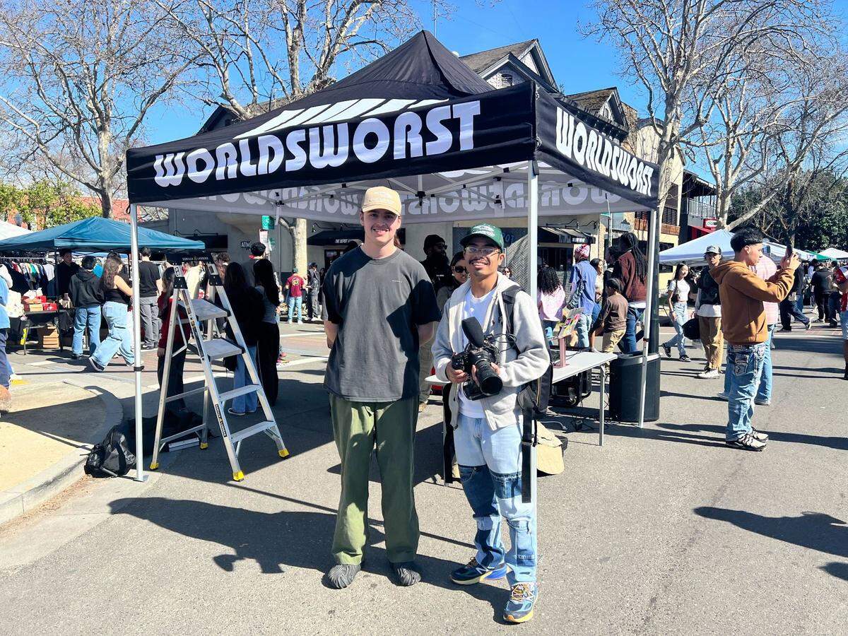 World’s Worst Expo co-owner Casey Mann, left, stands with videographer Tony Jelks-Tran in midtown Sacramento on Sunday. FIT CHECK: Mann is wearing a World’s Worst trucker hat, a thrifted ’90s t-shirt, ’80s military pants and Salehe Bembury Crocs.