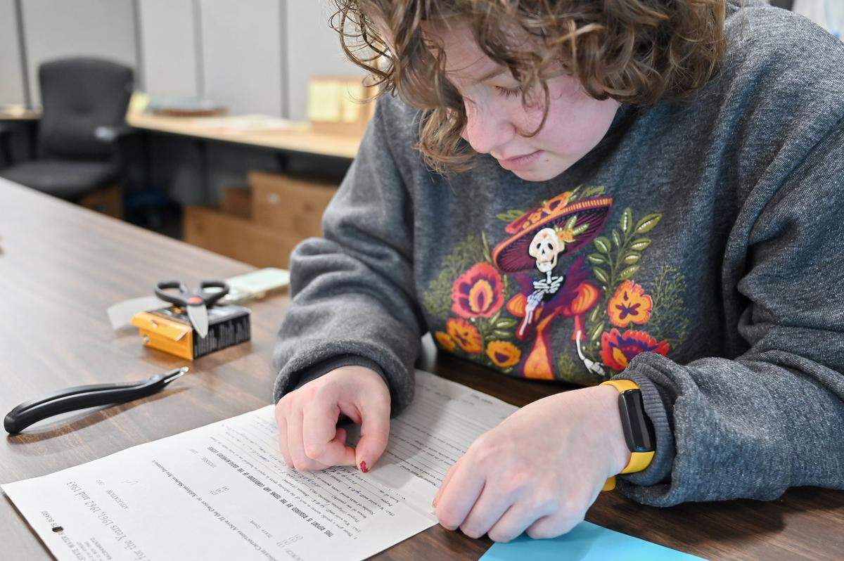 Student assistant Carmen Nehmer uses archival tape to repair a torn water rights document so it can be digitized with an automated document feeder.