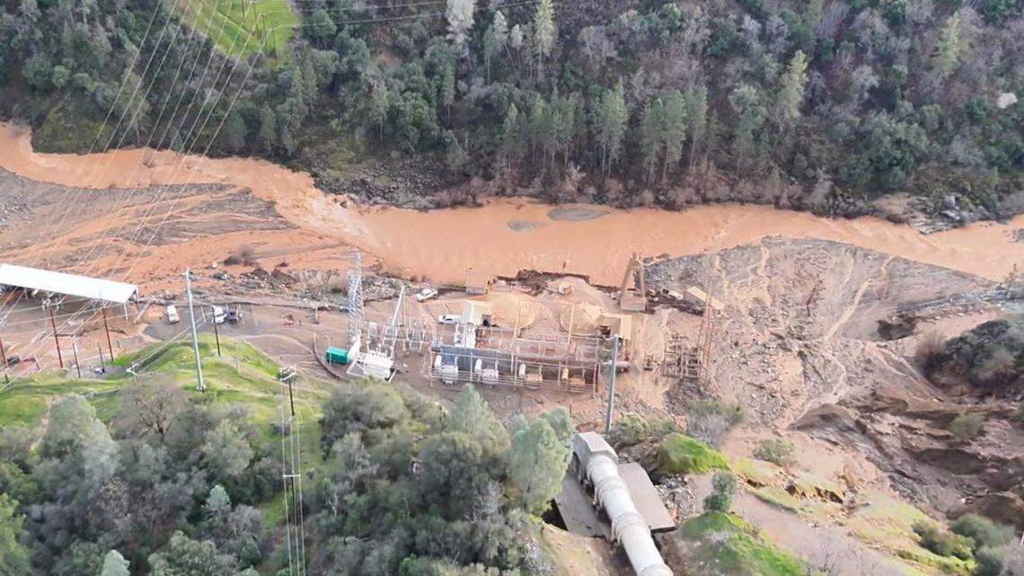 An aerial view shows floodwater washing over a roadway and around the New Colgate Powerhouse on Lake Francis Road in Dobbins on Friday, Feb. 13, 2026, after a penstock pipe burst. Rescue crews from Cal Fire Nevada Yuba Placer Unit and other agencies searched for and later found a missing worker, who was taken to a hospital.
