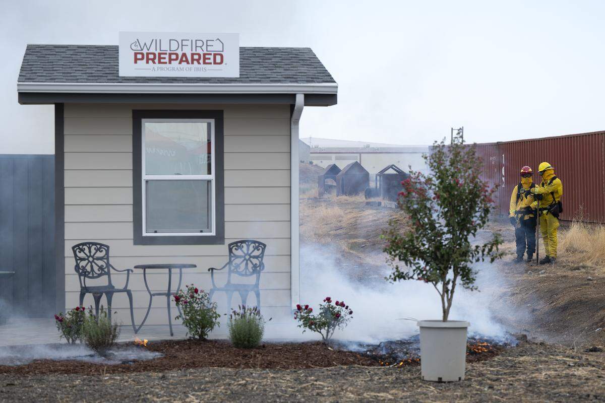 Firefighters watch a burn demonstration at the Sacramento City Fire Training Facility at McClellan Airfield on Wednesday, Sept. 24, 2025. The burn demonstrated the impact of proposed “zone zero’” regulations in a wild fire scenario.