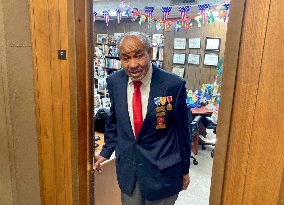 Rev. Wortham Fears stands in the doorway to his office at the Christian Cathedral in Oakland earlier this month, wearing his medals and the Navy blue blazer, white shirt and red tie that Montford Point Marines wear as part of their uniform.