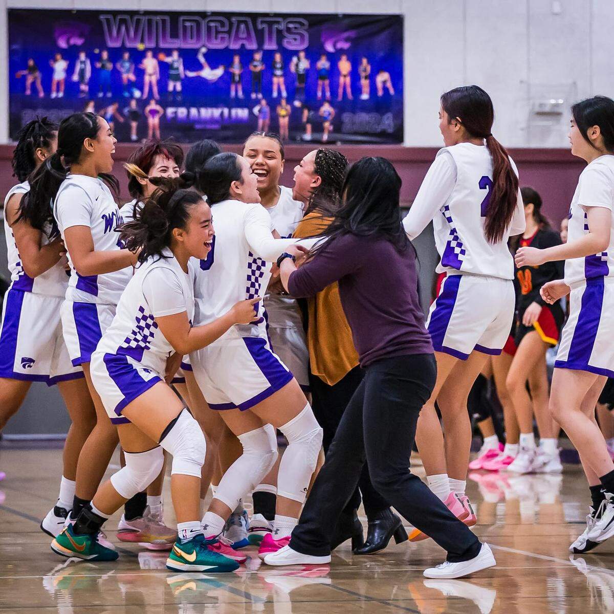 The Franklin Wildcats girls basketball team, led by coach Kim Manlangit, celebrates a 54-53 win over St. Francis on Jan. 12 at Franklin High School in Elk Grove.