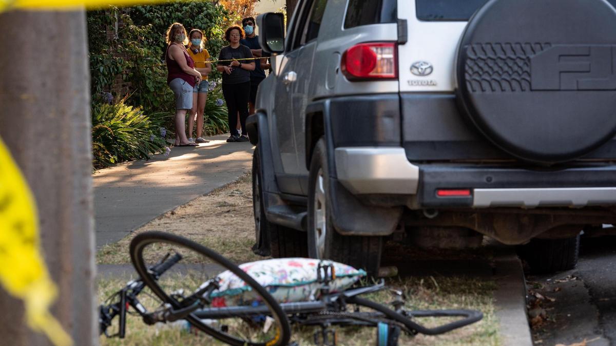 Neighbors watch as Sacramento police work where a vehicle hit a bicyclist on S Street near 26th Street, after hitting a separate bicyclist on 26th Street near P Street, on Thursday, July 16, 2020, in midtown Sacramento.