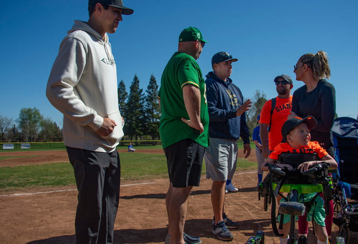 St. Louis Cardinals outfielder Dylan Carlson, left, waits to take a photo with the Jibben family – father Darren, mother Kayla and son Janeson – while they talk with Jason Jimenez, center right, who started Elk Grove youth baseball’s Championship Division, a league for players with cognitive or physical disabilities.