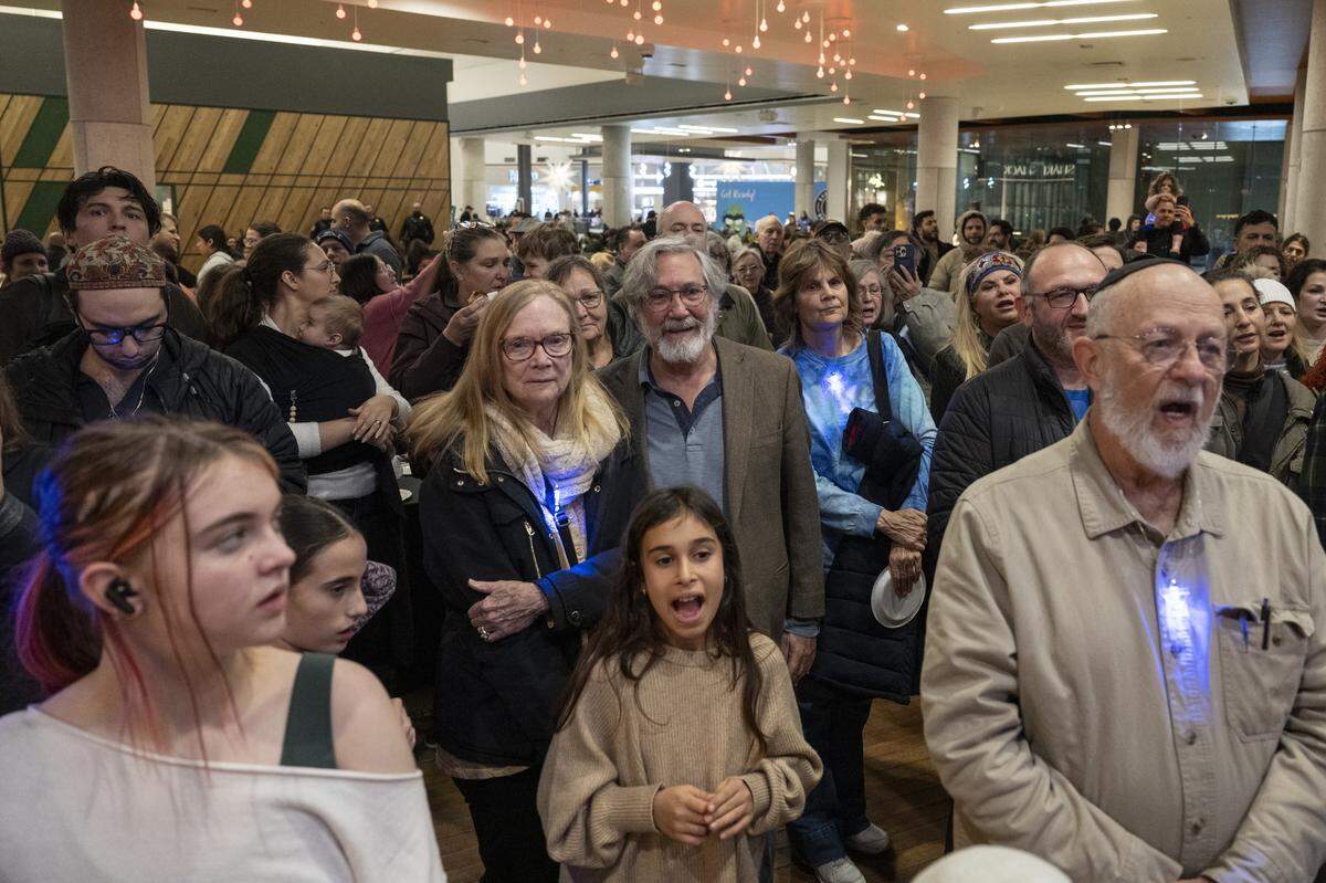 Members of the Roseville and Placer County Jewish community sing together during a menorah lighting on the first night of Hanukkah at the Westfield Galleria in Roseville on Sunday.