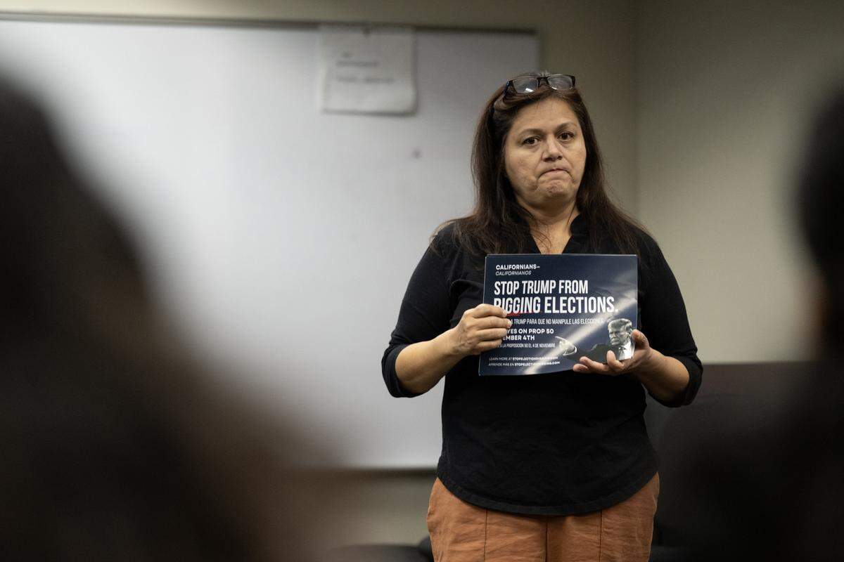 Hortencia Cabral, a school board member and president of the Democratic Women of Kern, holds a flyer that says "Stop Trump from rigging elections" as she speaks about Proposition 50 to a group of voters at a community meeting on Oct. 22 in Bakersfield. 