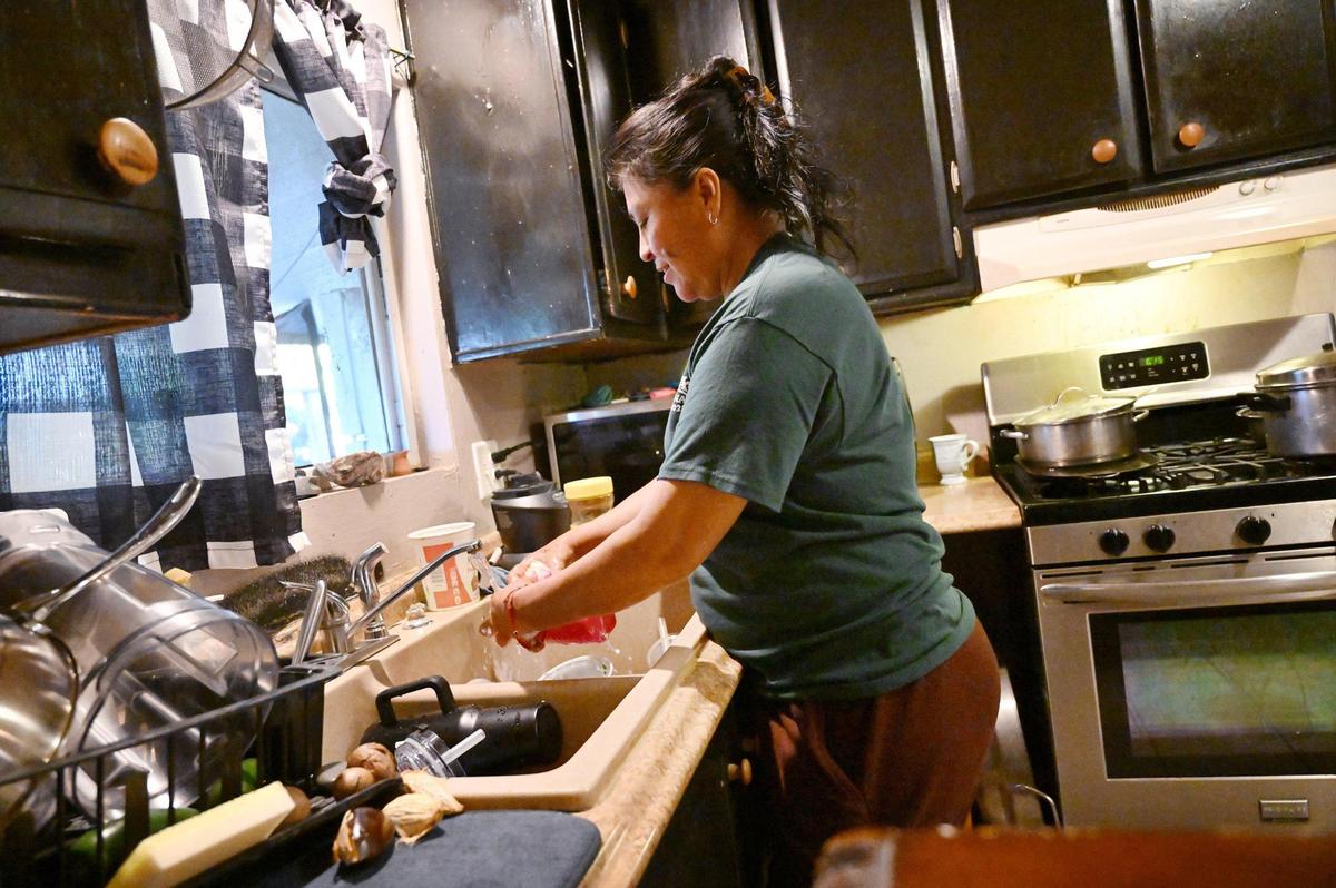 Xochilt Nuñez, who immigrated from Mexico in 1999, washes dishes at her home in an Orosi, small town 45 minutes from Fresno, on March 26. Nunez has spent years advocating for farmworker and immigrant&nbsp;rights and yet describes frustration and anger with the recent waves of migrants.