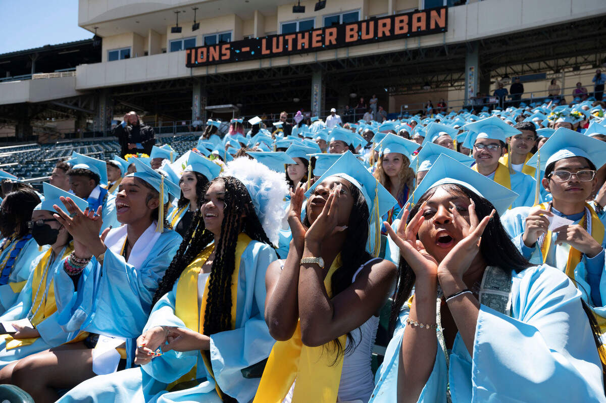 2022 graduates of Luther Burbank High School, including from right, Gabbby Moore, Shenaya Laud and Samia Embry, cheer on their classmates who walk the stage to receive their diplomas during the last graduation ceremony of the year for Sacramento Unified School District at Sutter Health Park in West Sacramento on Thursday, June 16, 2022.