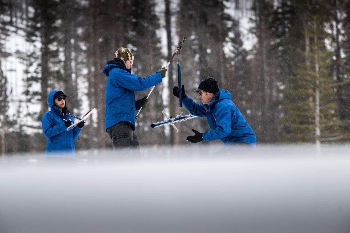 Hydrometeorologist Angelique Fabbiani-Leon, left, and water resources engineers Anthony Burdock and Andy Reising take measurements for the California Department of Water Resources as snow falls during a snow survey at Phillips Station in El Dorado County on Thursday, Feb. 29, 2024. The survey recorded 47.5 inches of snow depth and a snow water equivalent of 18 inches, which is 77% of normal.