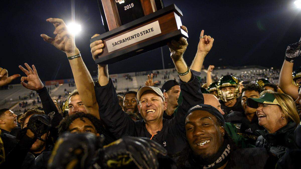 Sac State head coach Troy Taylor celebrates by holding up the Big Sky Conference trophy after the Hornets won the 66th Causeway Classic against UC Davis on November 23, 2019. The first-year football coachâs name has come up with other college openings. He is focused on leading the Hornets to their first FCS playoff against Austin Peay with plans to stay.