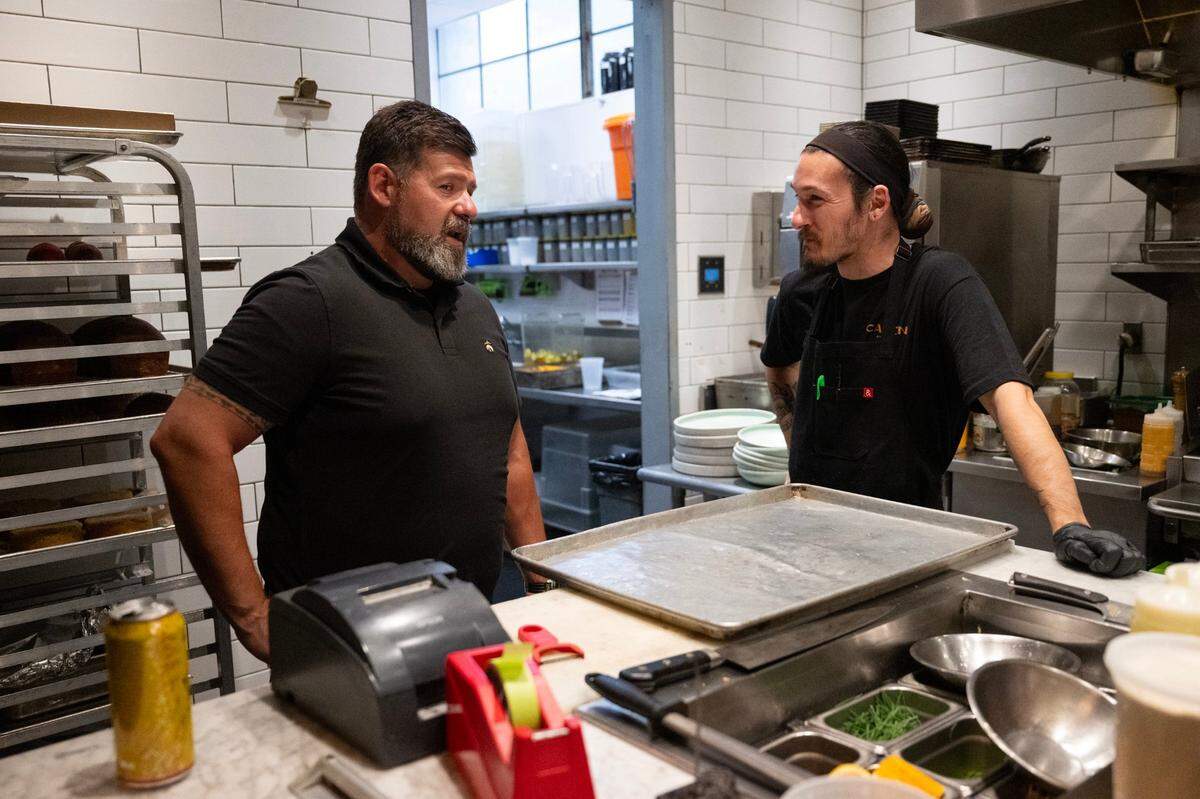 Canon restaurant co-owner Clay Nutting talks with Marques MacHale sous chef as the prepare for opening on Tuesday in East Sacramento. SB 478, also known as the Consumer Legal Remedies Act would ban restaurants from adding surcharges effective July 1.