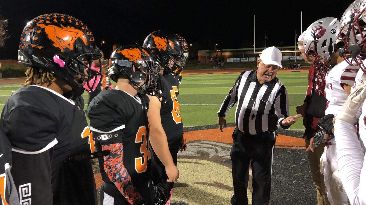 Foothill and Bear River captains check out the coin with the official Friday.