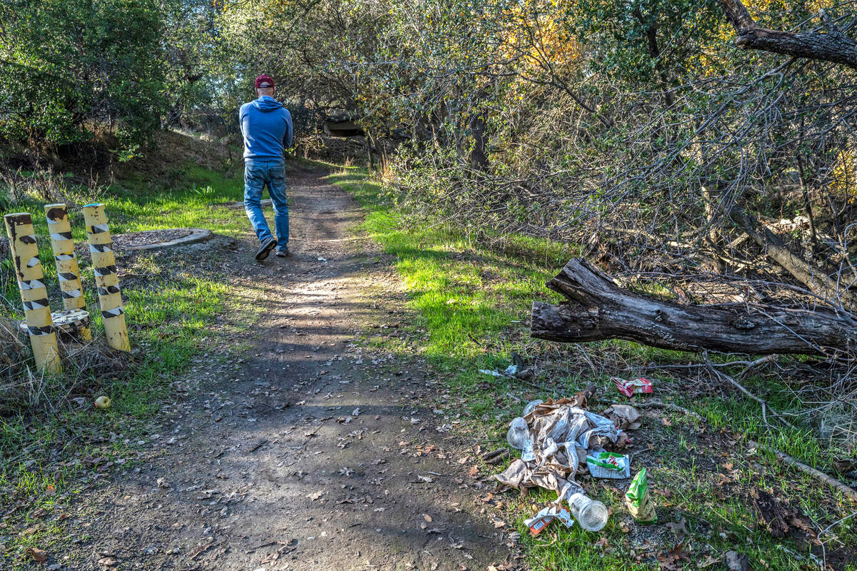 Charlie Duckworth walks past a pile of trash on a path in the Del Paso Regional Park earlier this month behind the Hope Cooperative Outreach and Engagement Center property. Duckworth lives near the park, which he says has been impacted by homeless from the center. “We are adding homeless. We are adding problems,” said Duckworth.