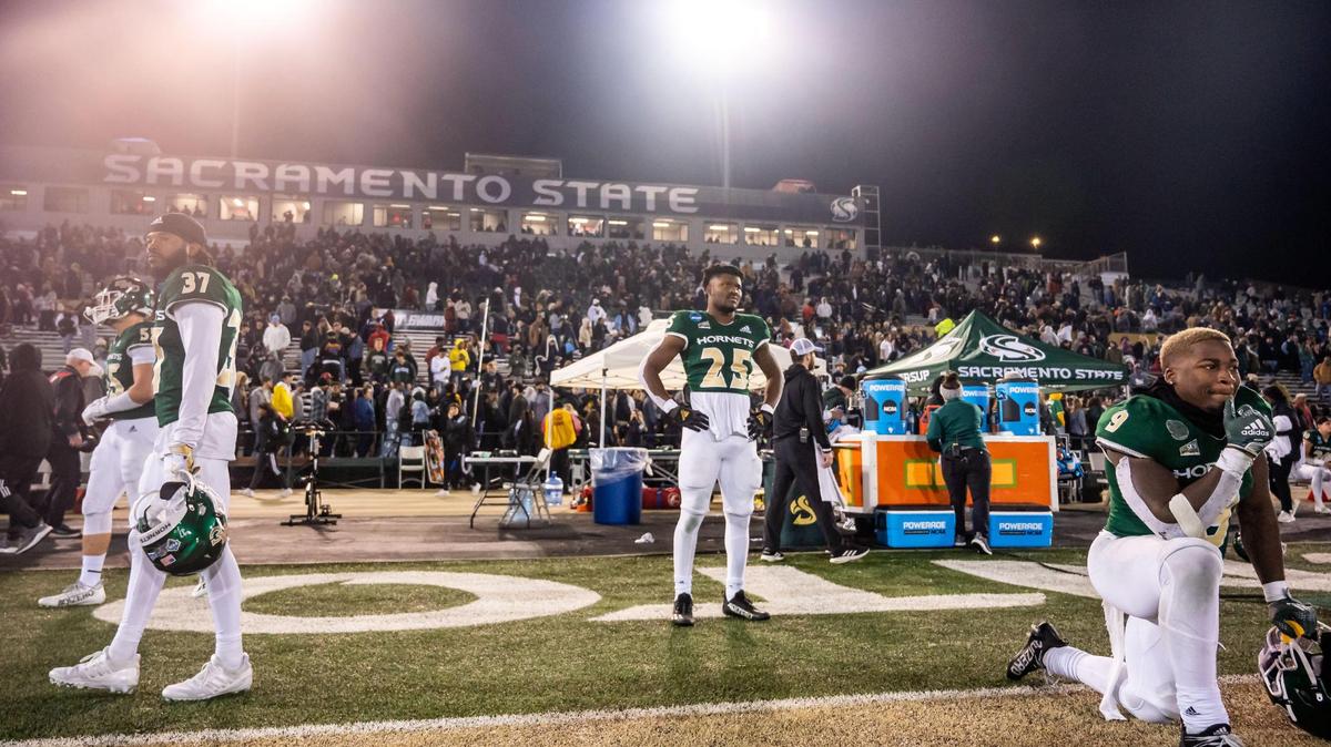 Sacramento State Hornets running back Marcus Fulcher (9), right, running back Elijah Tau-Tolliver (25), center, and cornerback Dilon Juniel (37) watch quietly as Incarnate Word players celebrate their 66-63 win at the NCAA college football FCS playoffs quarterfinal game Friday at Hornet Stadium.