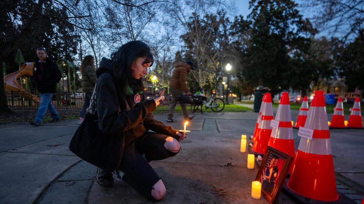 During a vigil hosted by Slow Down Sacramento for people killed in city traffic collisions, Lunden Almquist takes a picture of a framed photograph in front of a cone on Thursday, Jan. 2, 2025. The photograph shows her late stepfather, José Luis Silva, who was killed in 2024 while riding his motorcycle in midtown. Sacramento has pledged to eliminate traffic deaths, but data show the city still has some of the most dangerous roads in California. 
