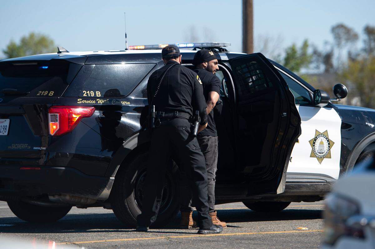 A man is escorted to a sheriff’s vehicle after a shooting at the Sacramento Sikh Society Temple, it is unknown if he was involved, on Sunday, March 26, 2023, in Sacramento. The shooting occurred during the Sacramento Sikh Society’s first Nagar Kirtan Parade.