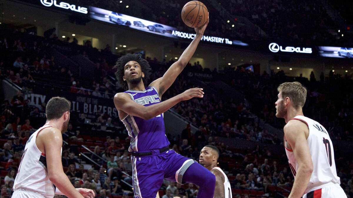 Kings forward Marvin Bagley III shoots between Portland Trail Blazers center Jusuf Nurkic, left, and forward Jake Layman, right, during the first half of an NBA preseason basketball game in Portland, Ore., Friday, Oct. 12, 2018.