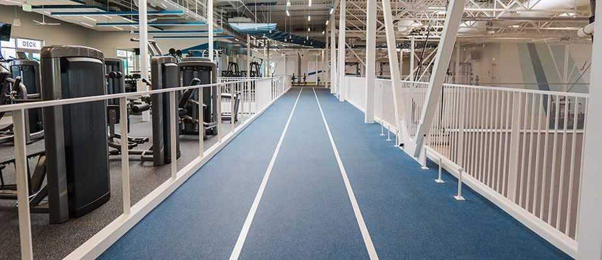 An elevated indoor track encircles the gym floor at CORE in Elk Grove, offering views of the courts and nearby weight-training zones. The facility integrates multiple fitness areas under one roof.