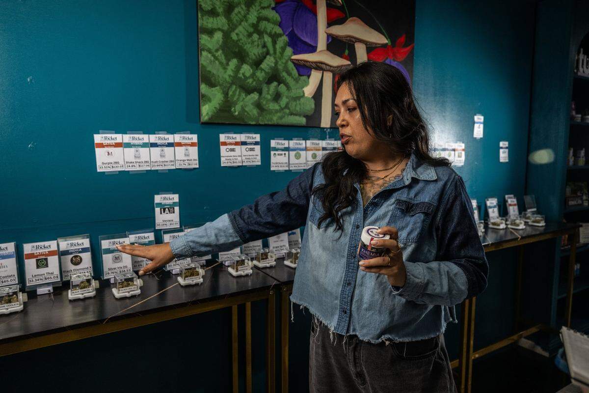 Mindy Galloway, owner of The Pocket Dispensary in Sacramento, points to products in her store last month. Owners of local cannabis businesses argue that taxes are too high on their products, making it difficult to compete with illegal and unregulated products.