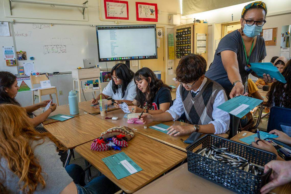 Sacramento County elections office assistant Kinu Van Vorhis passes out ballets during a mock election at West Campus High School in Sacramento on Wednesday, Oct. 2, 2024. Students picked between fictional candidates, such as superhero secret identities Tony Stark and Peter Parker, as they learned about the voting process.