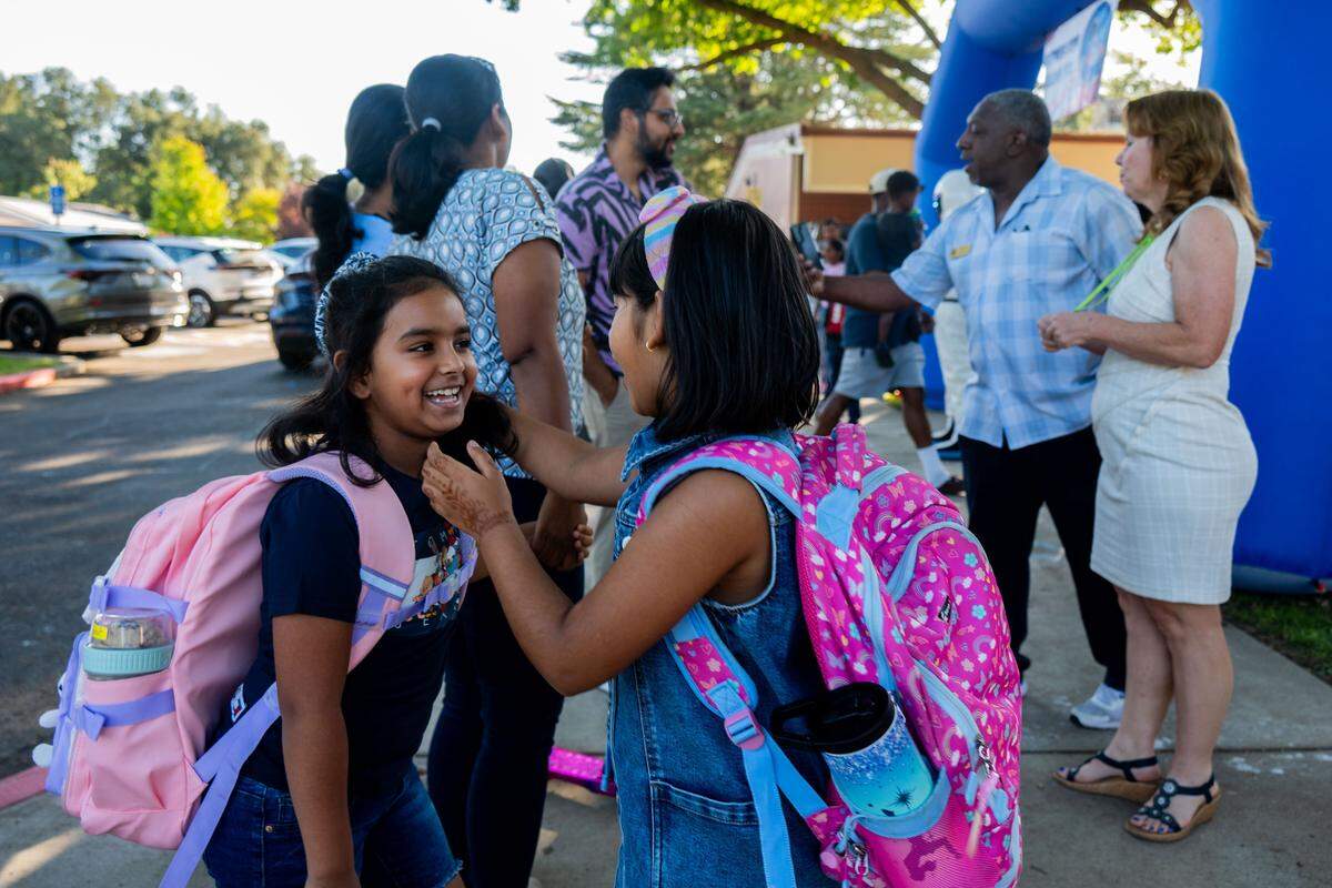 Second graders Anahat Singh, left, and Sarah Tinmaker, right, excitedly play while their parents chat with staff on the first day of school at Riverview STEM Academy on Thursday, Aug. 7, 2025. The two have been friends since kindergarten.