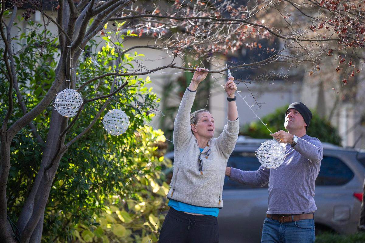 Lindsey and Steven Anderson hang holiday lights outside their home on Santa Inez Way following the morning rain in Sacramento on Saturday, Dec. 13, 2024.