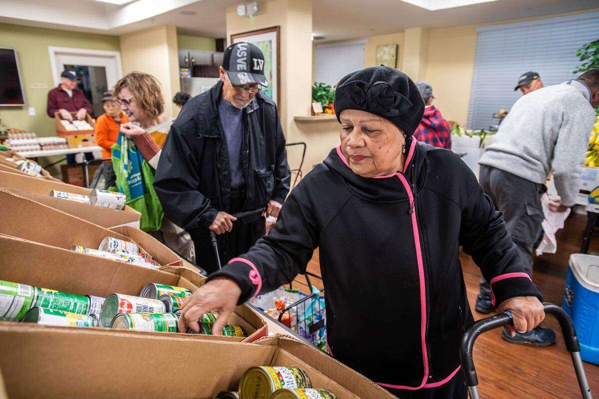 Arbor Creek Family Apartments resident Miriam Cruz gathers groceries donated by the Elk Grove Food Bank Services on Nov. 21. The organization asks Book of Dreams readers for donations to resume their mobile cooking classes for seniors.
