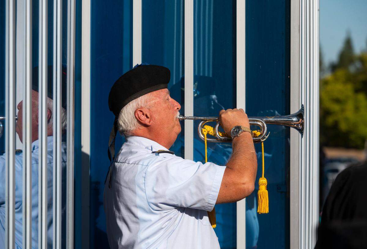 Lt Cmdr. Bill Tubbs (retired) of the United States Coast Guard Pipe Band is reflected in the monument of the World Trade Center as he plays the bugle after the wreath laying at the 9/11 Memorial Ceremony at Cal Expo on Saturday, Sept. 11, 2021, the 20th anniversary of the attack.