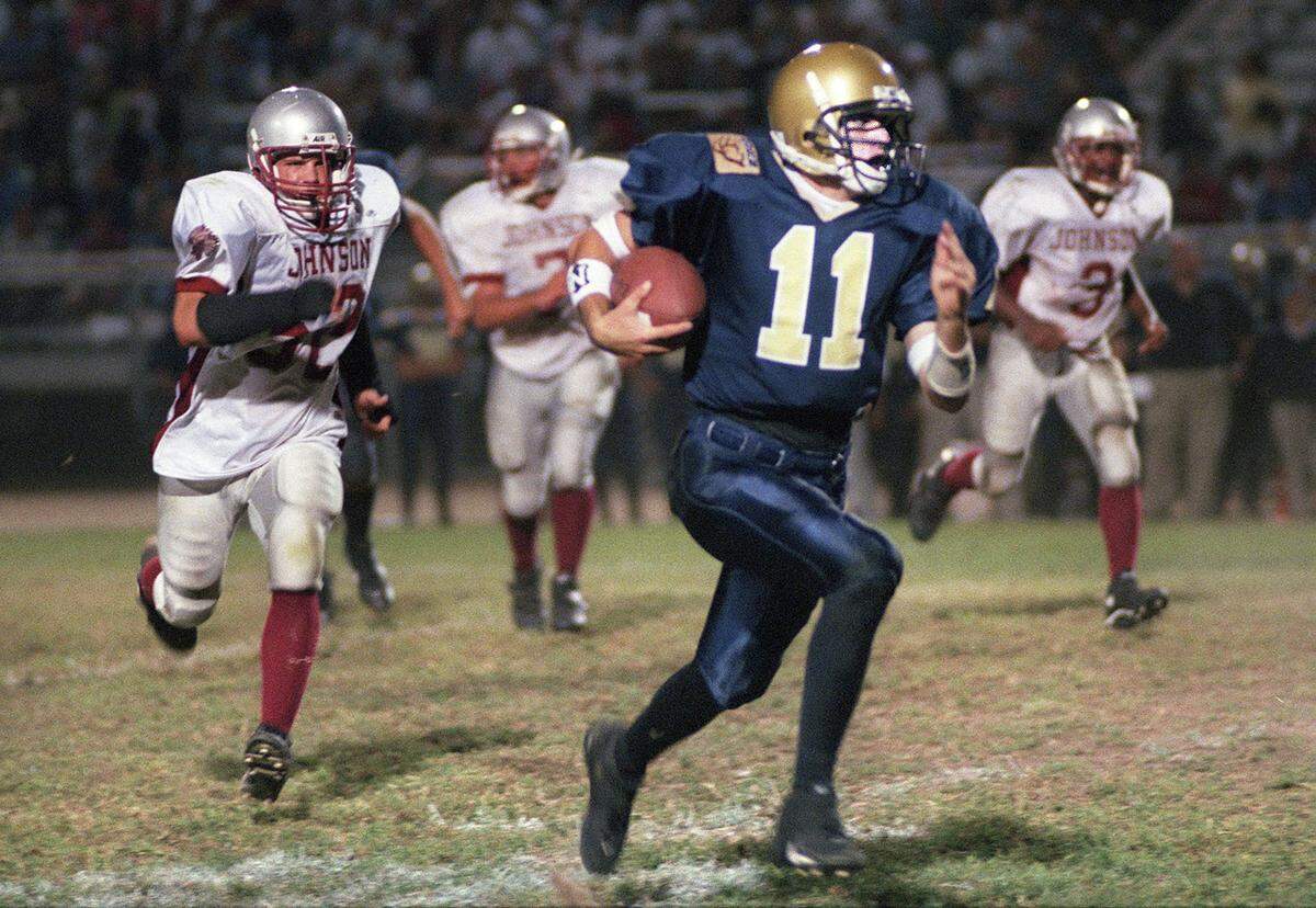 Elk Grove Thundering Herd quarterback Ryan Dinwiddie (11) takes the ball to the 21-yard line against Hiram Johnson High School in 1998 in Elk Grove.  