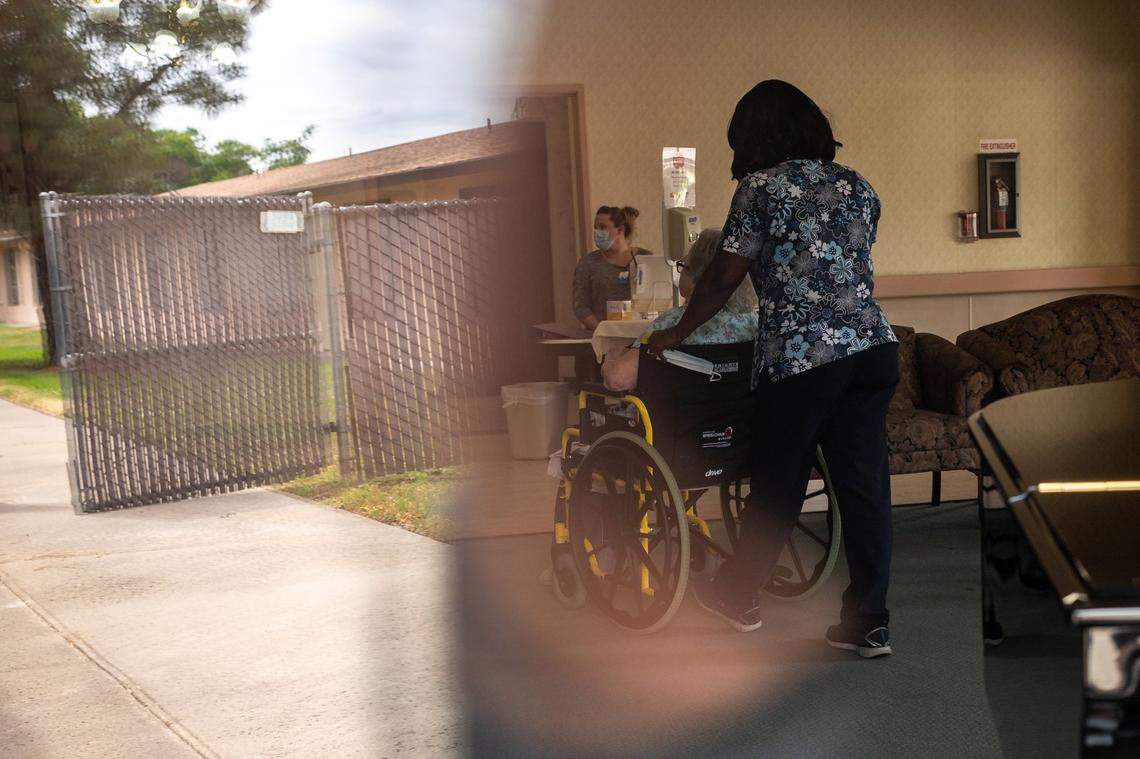 Seen through a window, a nurse pushes a patient  in a wheel chair at City Creek Post Acute — formerly Saint Claire's Nursing Center — on May 14, 2020, in south Sacramento.