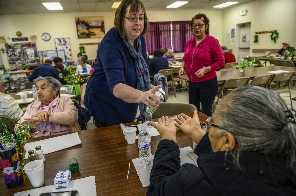 Julie Rhoten, executive director of the Stanford Settlement Neighborhood Center, passes out hand sanitizer to seniors after talking to them about safety precautions for the coronavirus on Monday, March 9, 2020, in Sacramento.
