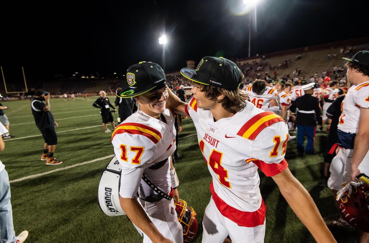 After collecting hats commemorating the 50th Holy Bowl, Jesuit’s Cormac O’Flaherty, right, congratulates teammate Trenton Dewar on their win over Christian Brothers during the high school football rivalry game in September at Hughes Stadium in Sacramento. Both players return in 2022.
