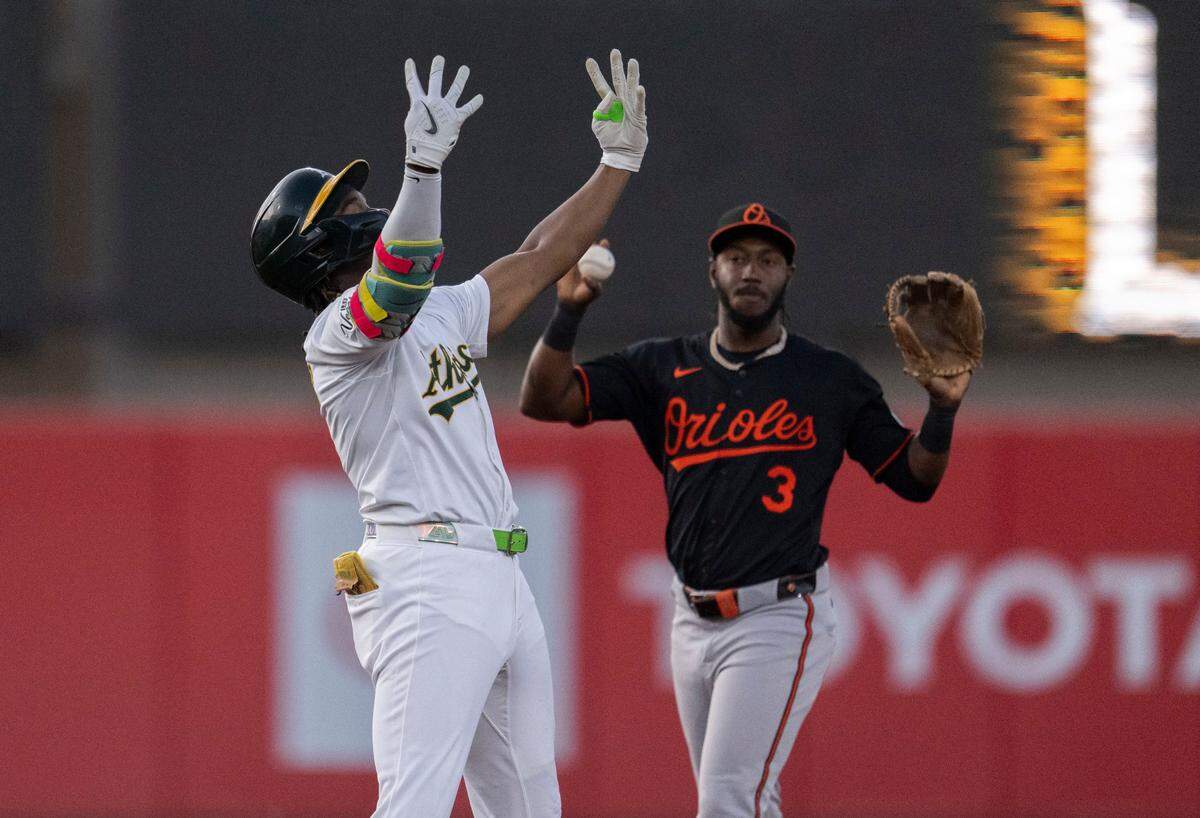 Athletics outfielder Lawrence Butler celebrates a two-run RBI in the third inning as Baltimore Orioles shortstop Jorge Mateo (3) holds the ball at Sutter Health Park on Friday.