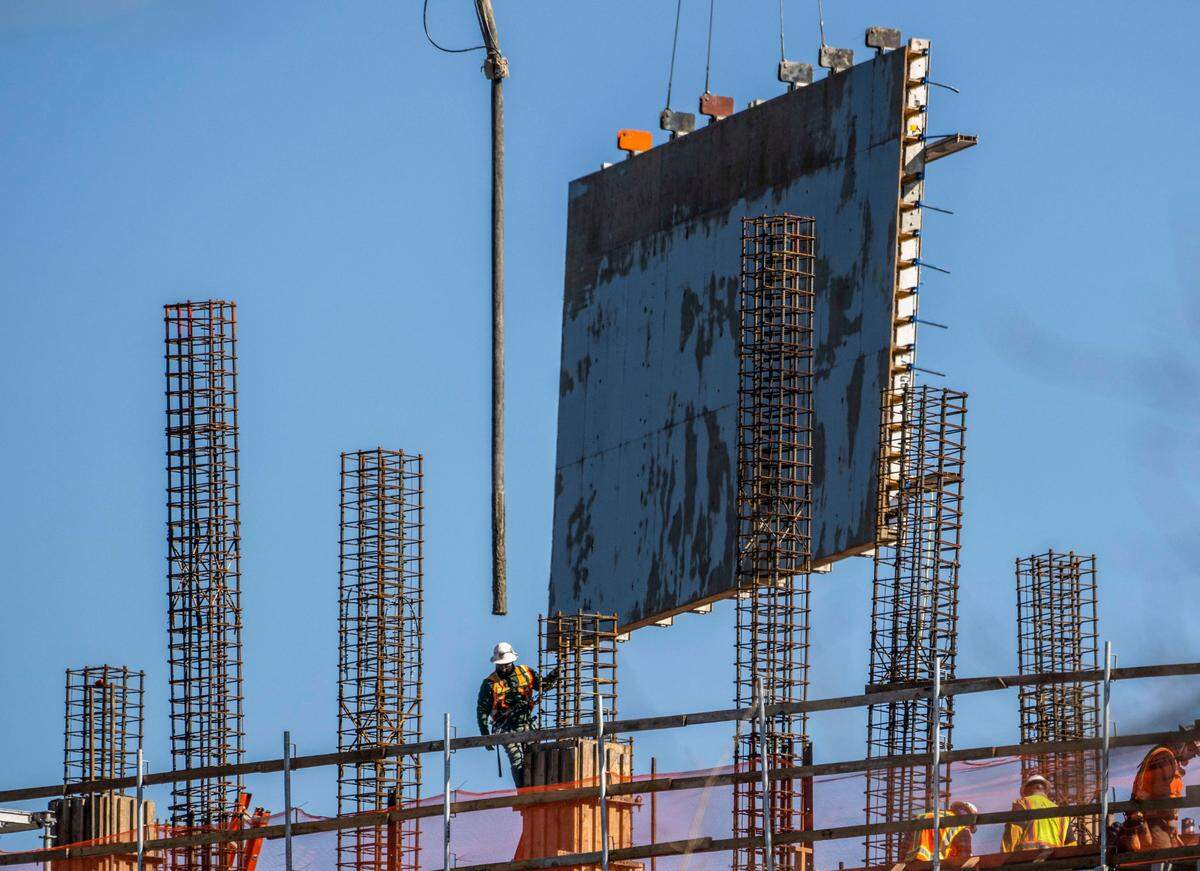 A wall is moved into place as a construction worker loads a steel column with concrete during construction of Aggie Square at the UC Davis Sacramento campus on Tuesday.